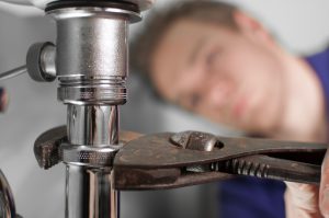 Plumber doing some work under the sink. Tightening siphon.